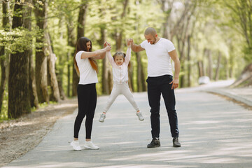 Family in a summer forest. Woman and man in a white t-shirts. Daughter with parents.