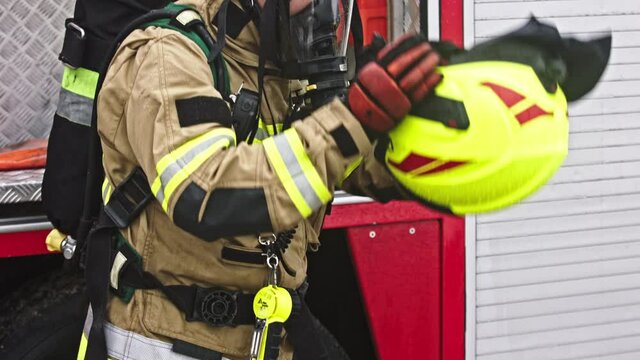 Fireman with gas mask putting on safety hemet in front of the fire engine. High quality 4k footage