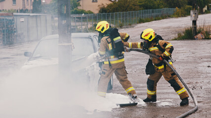 Firefighters extinguish fire from the burning car using foam. High quality photo