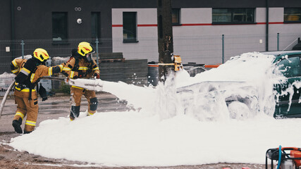 Firefighters extinguish fire from the burning car using foam. High quality photo