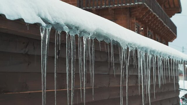 Snowfall and snowflakes on the background of wooden wall with icicles and snowdrift. Winter Christmas theme. Slow motion, Full HD video