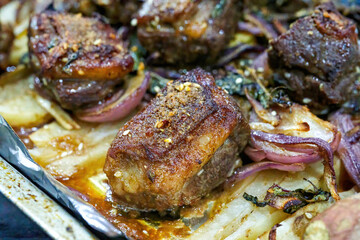 Closeup of a plate of grilled lamb chops with onions and potatoes