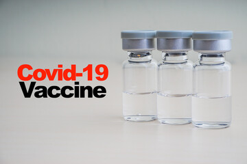 COVID -19 VACCINE text with vials on wooden background. Coronavirus or Covid-19 Vaccine concept
