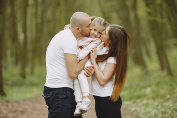 Family in a summer forest. Woman and man in a white t-shirts. Daughter with parents.