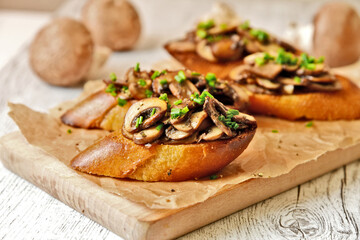 Champignon or brown cap mushroom Crostini on brown paper and wooden board.