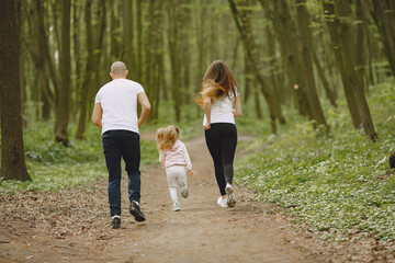 Obraz premium Family in a summer forest. Woman and man in a white t-shirts. Daughter with parents.