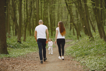 Family in a summer forest. Woman and man in a white t-shirts. Daughter with parents.