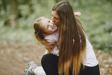 Fototapeta premium Family in a summer forest. Woman in a white t-shirt. Daughter with mother.