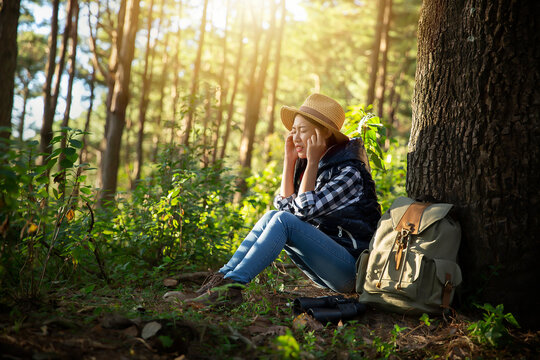Woman With Headache Sitting Against Trees In Forest