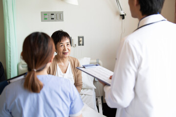 回診に来た医者と話す入院患者の女性と家族