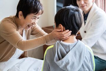 お見舞いに来た孫の頭を撫でる祖母	
