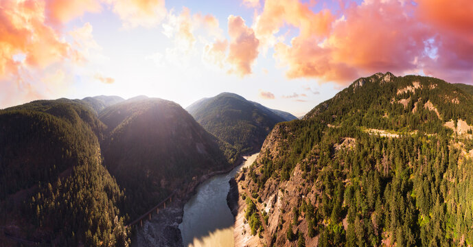 Beautiful Panoramic View of Canadian Nature and a Scenic Road, Trans-Canada Hwy. Dramatic Colorful Sunset Sky Art Render. Aerial Drone Shot. Near Hells Gate, BC, Canada.