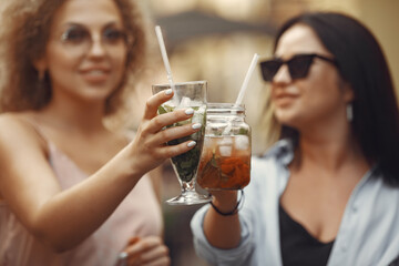 Women in a summer city. Friends drinks cocktails.