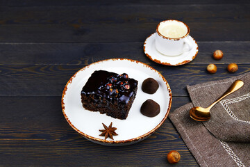 Homemade chocolate brownies and cup of coffee on a dark wooden background.