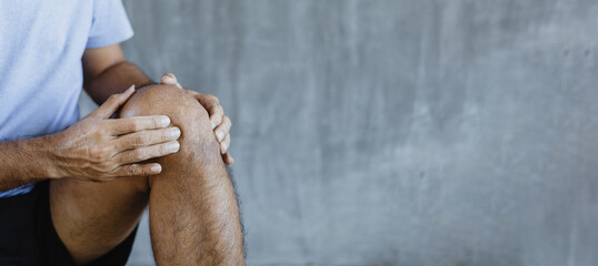 young man knee ache on against a gray background with copy space, healthcare concept