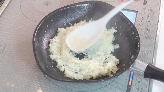 みじん切りにした玉ねぎをフライパンで炒めていく様子
