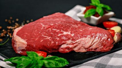 Food banner raw beef steak. Pasture raised meat with spices and herbs on a dark background.