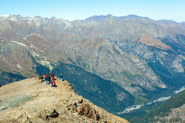 Fototapeta premium Tourists on Mount Mussa-Achitara look at the Alibek gorge. Dombay. Karachay-Cherkessia. Russia