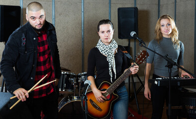 Fototapeta na wymiar expressive excited young group of rock musicians posing with instruments in recording studio