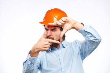 A man in a working uniform orange hard hat gestures with his hands emotions Construction engineer Professional