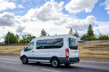 Compact commercial mini van with dark glass windows running on the highway road with cloud sky