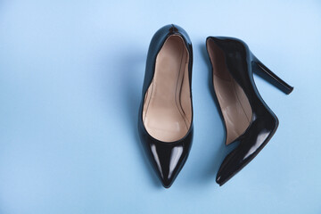 Black high heeled shoes on blue background. Feminine stylish shoes.