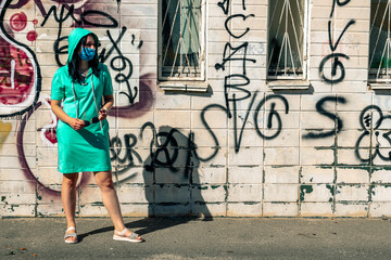 Woman in face mask near the wall with graffiti