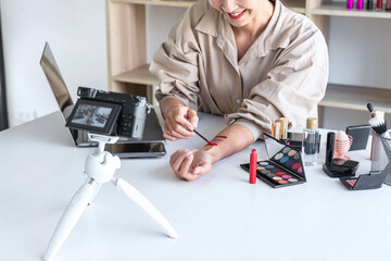 Happy smiling elegant woman or beauty blogger with brush on recording video while review product...