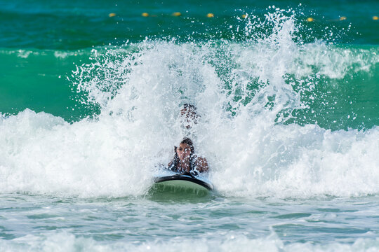 Tourists surfing against waves at Jumeirah Beach, a famous resort in Dubai, United Arab Emirates