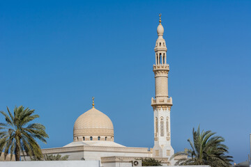 Fototapeta premium The dome and minaret of Maharba mosque and palm tree against blue sky in Dubai, United Arab Emirates.