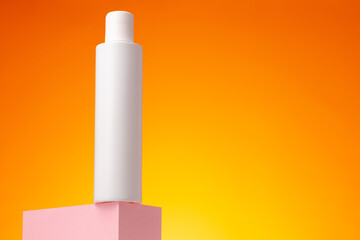 Blank white cosmetic container against orange background