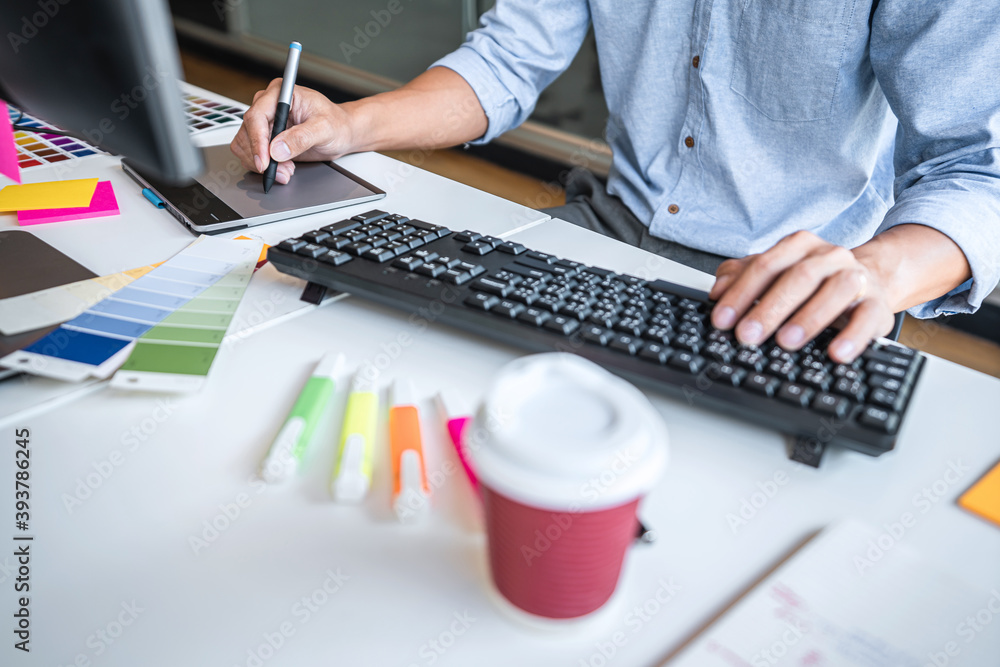 Poster Image of male creative graphic designer working on color selection and drawing on graphics tablet at workplace with work tools and accessories in workspace