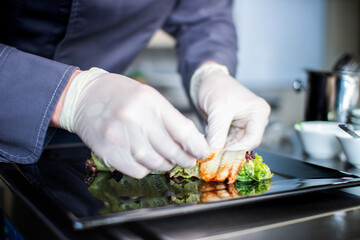 closeup chef preparing salad with eel cucumbers and lettuce leaves on mat