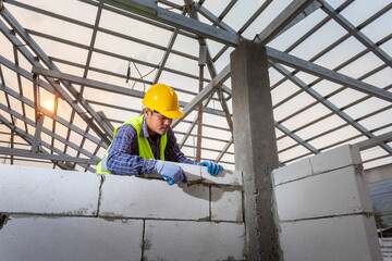 Asain worker bricklayer builder working with autoclaved aerated concrete blocks. Walling,...