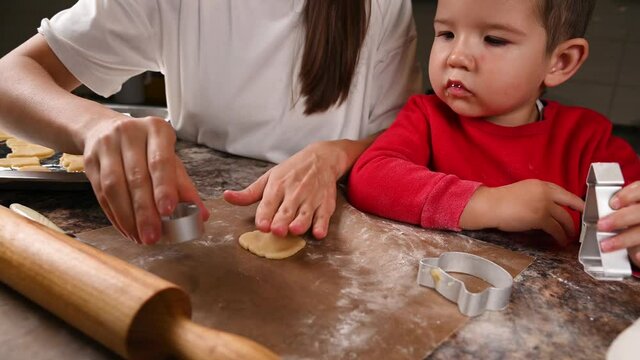Mom and baby roll out the dough. Cooking in the kitchen