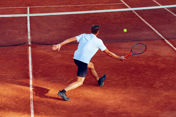 Back view of a man playing tennis on tennis court