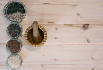 Chia, flax, sesame, pumpkin seed and sunflower seed with mortar and pestle on a wooden base.