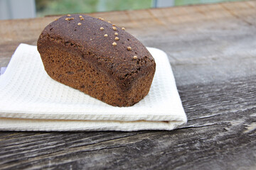 Homemade dark brown sourdough rye bread of Russian origin with coriander and caraway seeds on rough Board background.