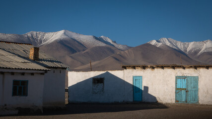 Scenic landscape view of Karakul village houses with snow-capped mountain background, Murghab district, Gorno-Badakshan, Tajikistan Pamir