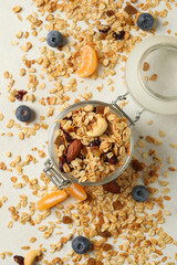 Glass jar with tasty granola on white background