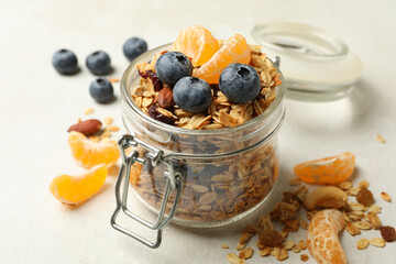 Glass jar with tasty granola on white background
