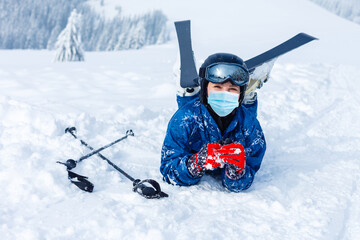Portrait of a woman skier in medical mask during COVID-19 coronavirus on a snowy mountain at a ski...