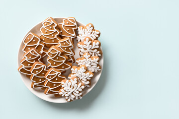 Christmas gingerbread cookies in plate on light blue background. Merry Christmas and Happy New Year greeting card with copy space. View from above.