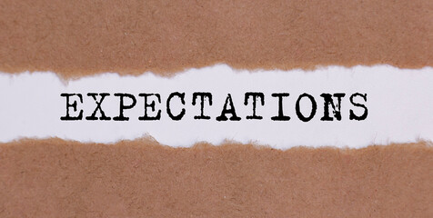 Expectations word written behind torn paper. business