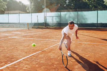 Fit man plays tennis on tennis field