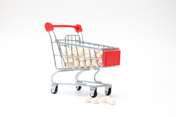 Pills and capsules in shopping cart on white background