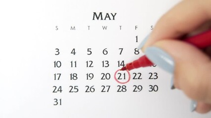 Female hand circle day in calendar date with a red marker. Business Basics Wall Calendar Planner and Organizer. May 21th