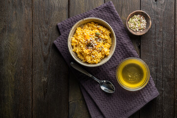 Millet porridge with pumpkin, honey and pumpkin seeds on a dark background. Rustic table with healthy breakfast.
