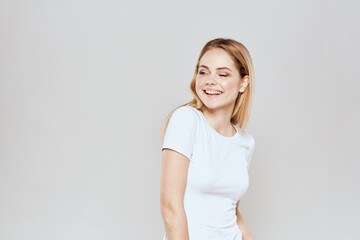 Fototapeta premium cheerful blonde in a white t-shirt gesturing with her hands light background