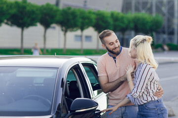 Fototapeta na wymiar Happy young couple, man and woman inspect a new car. Car sale. Buying a new car